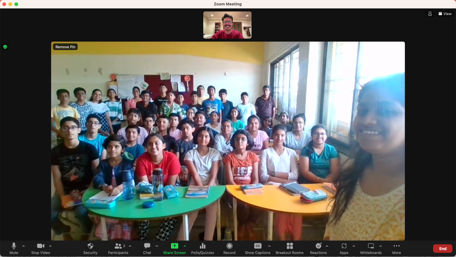 A group of adolescents in a classroom with their teachers. The author of the post can been seen in a Zoom window.